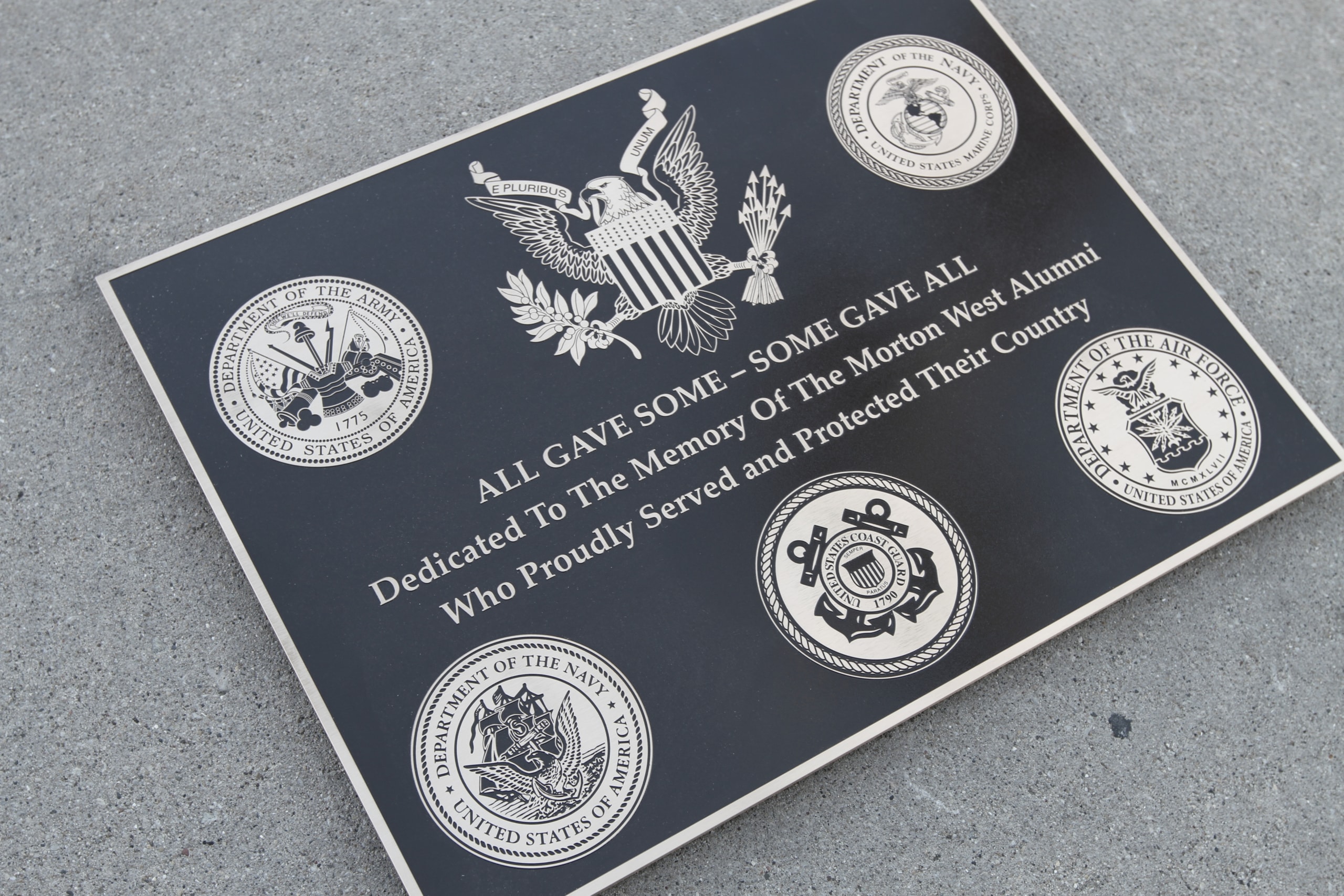 A cast bronze Veteran's Day memorial plaque located at Morton West High School in Berwyn, Illinois. It shows the seals of the Army, Marine, Navy, Air Force, and Coast Guard.