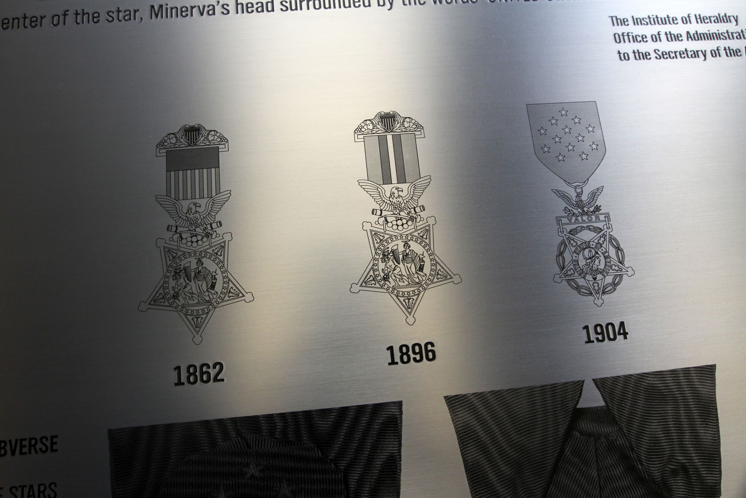 A close-up of another etched stainless steel plaque at the National Museum of the Army. This memorial displays detailed etchings of Army medals from 1862, 1896, and 1904.