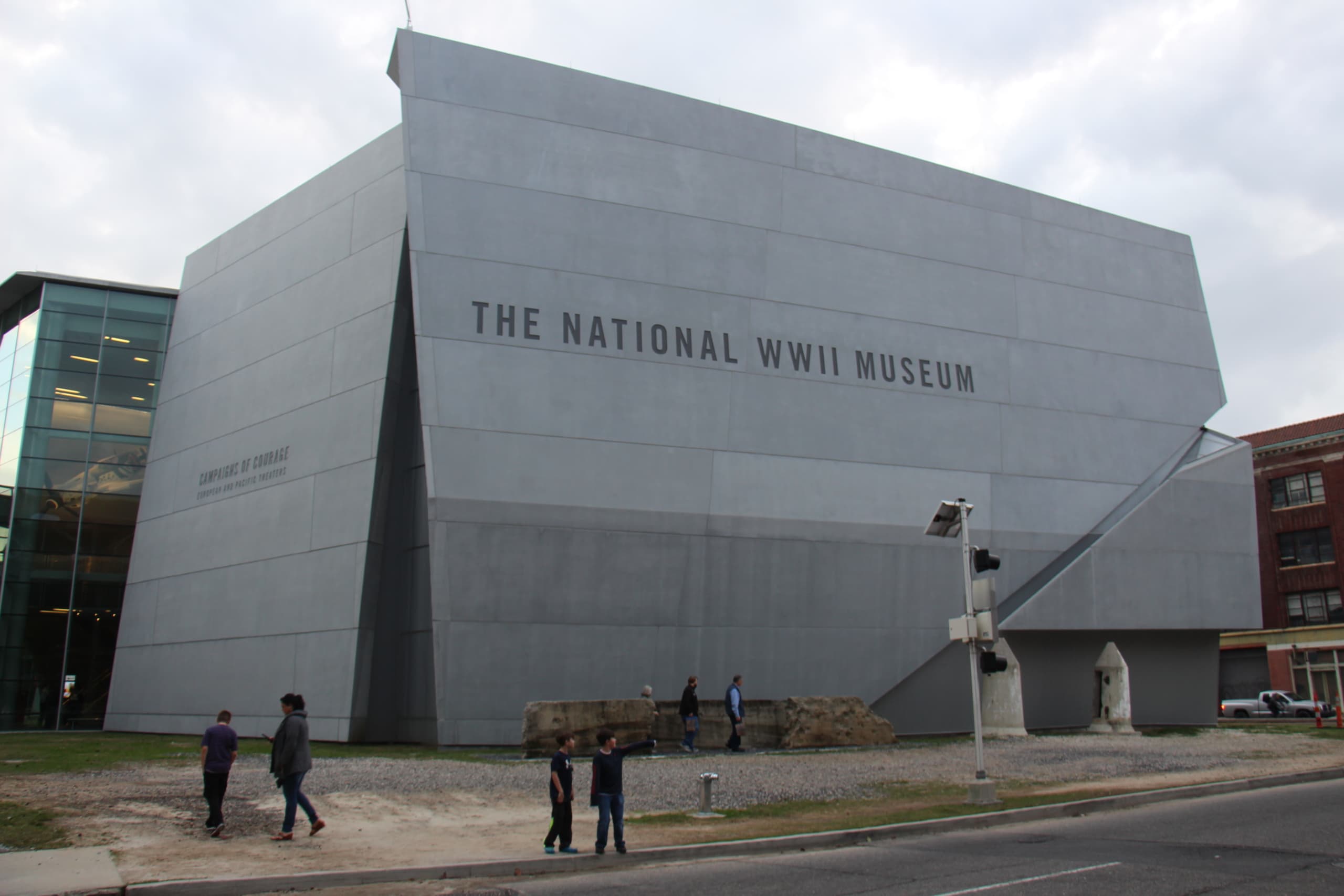 The World War II museum, with several visitors standing outside. The museum offers immersive exhibits and preserves the story of WWII while honoring those lost during the events.