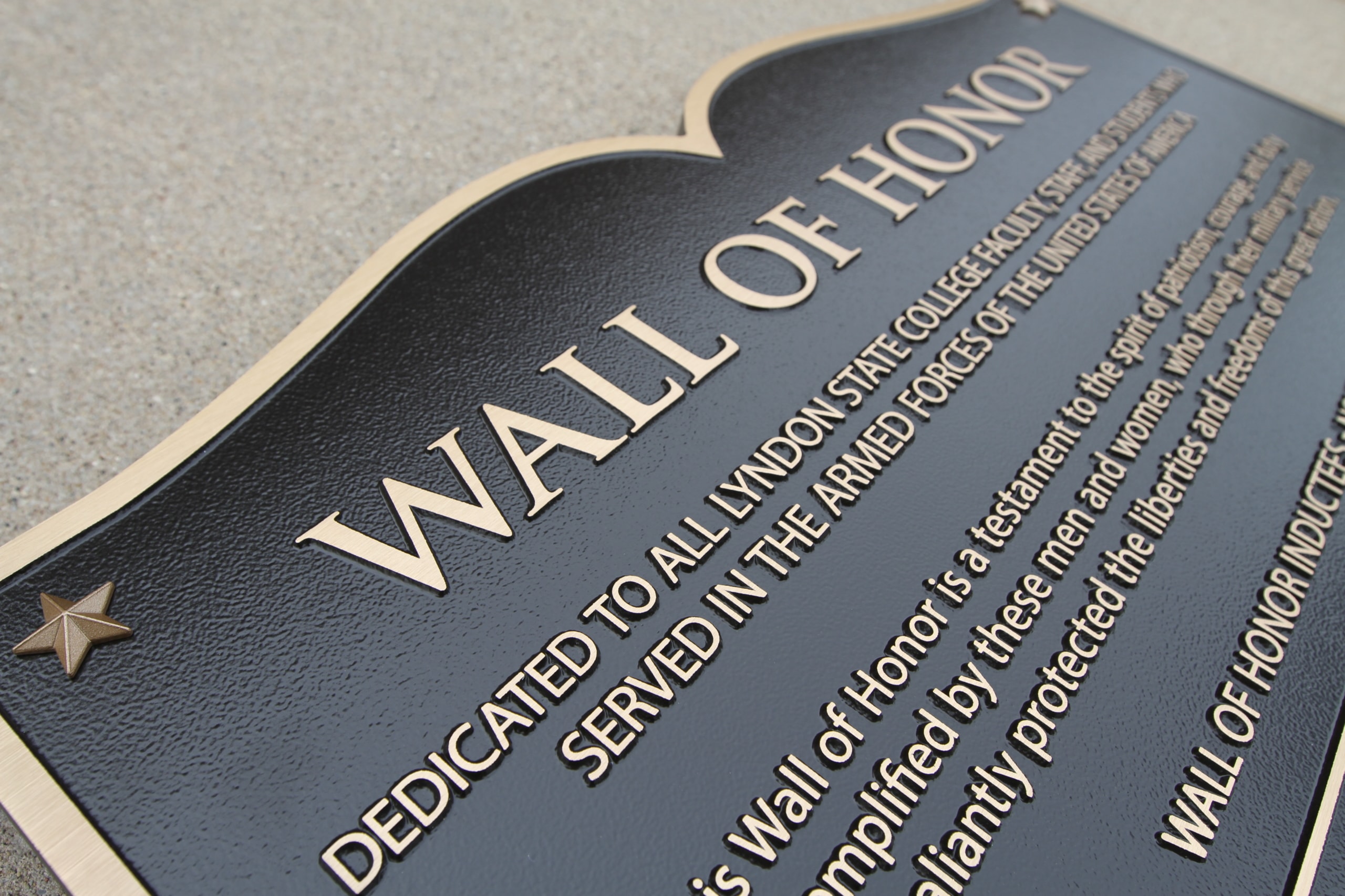 An example of a wall of honor, this close-up photo of a cast bronze plaque shows that it is dedicated to Lyndon State College Faculty in Lyndon, Vermont.