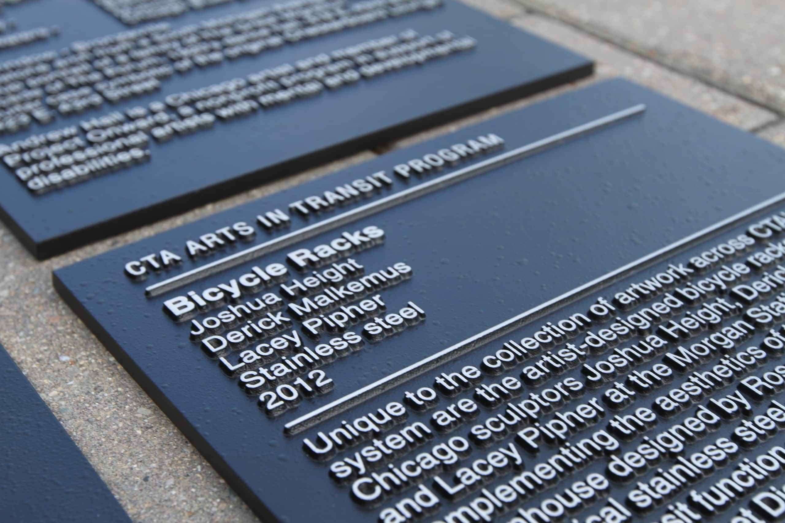 A wayfinding sign with cut metal letters providing information on a local program in Chicago called “CTA Arts in Transit.”