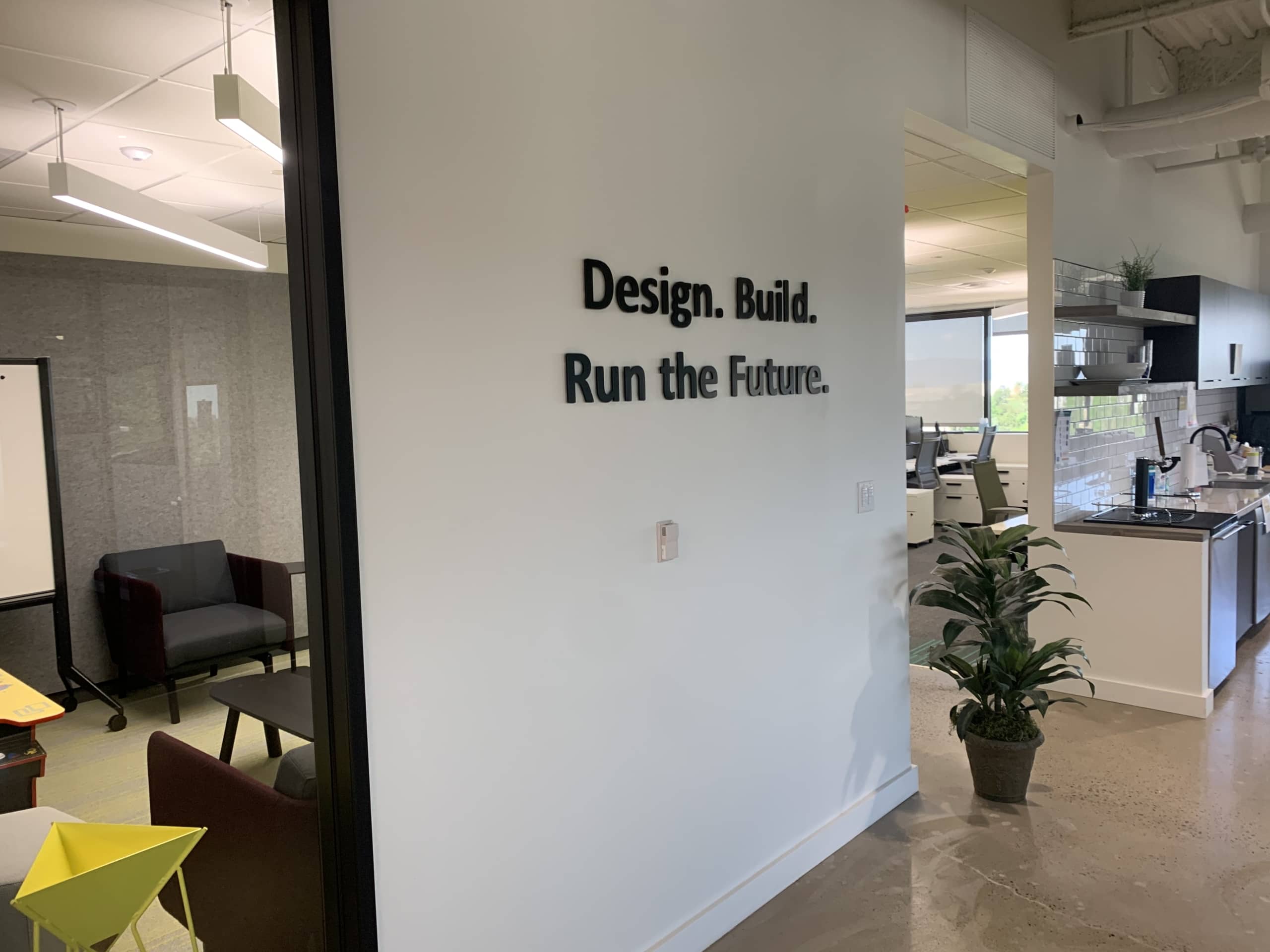 An example of visual communication in a workplace — acrylic letters spelling the words, “Design. Build. Run the future.”