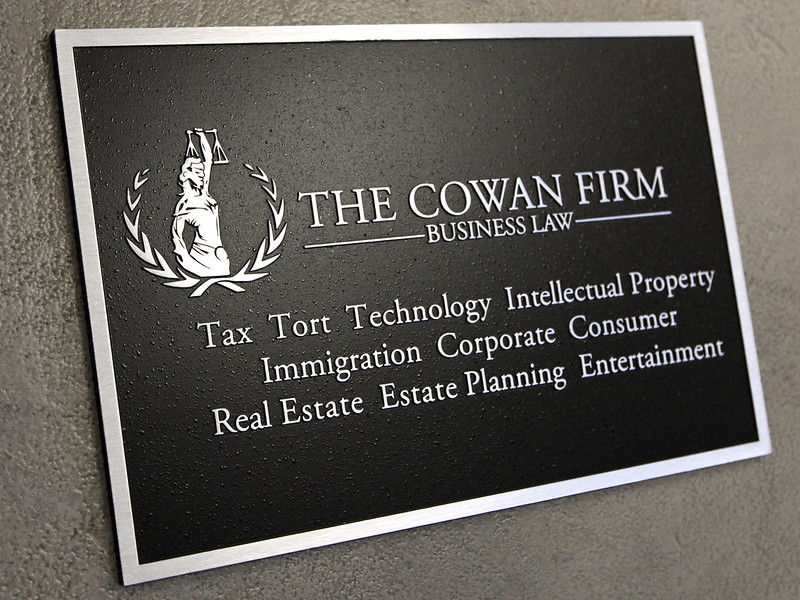 Metal plaque welcome sign with name and service details of the firm