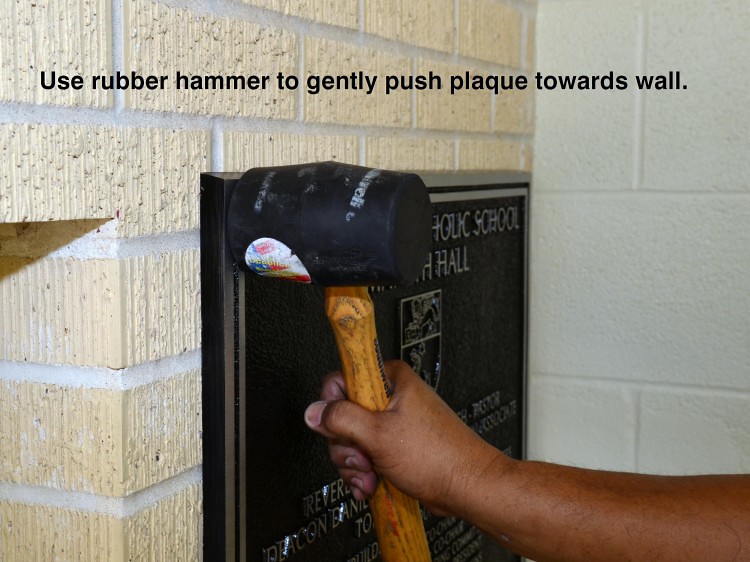 Use a rubber hammer to push the plaque towards the wall