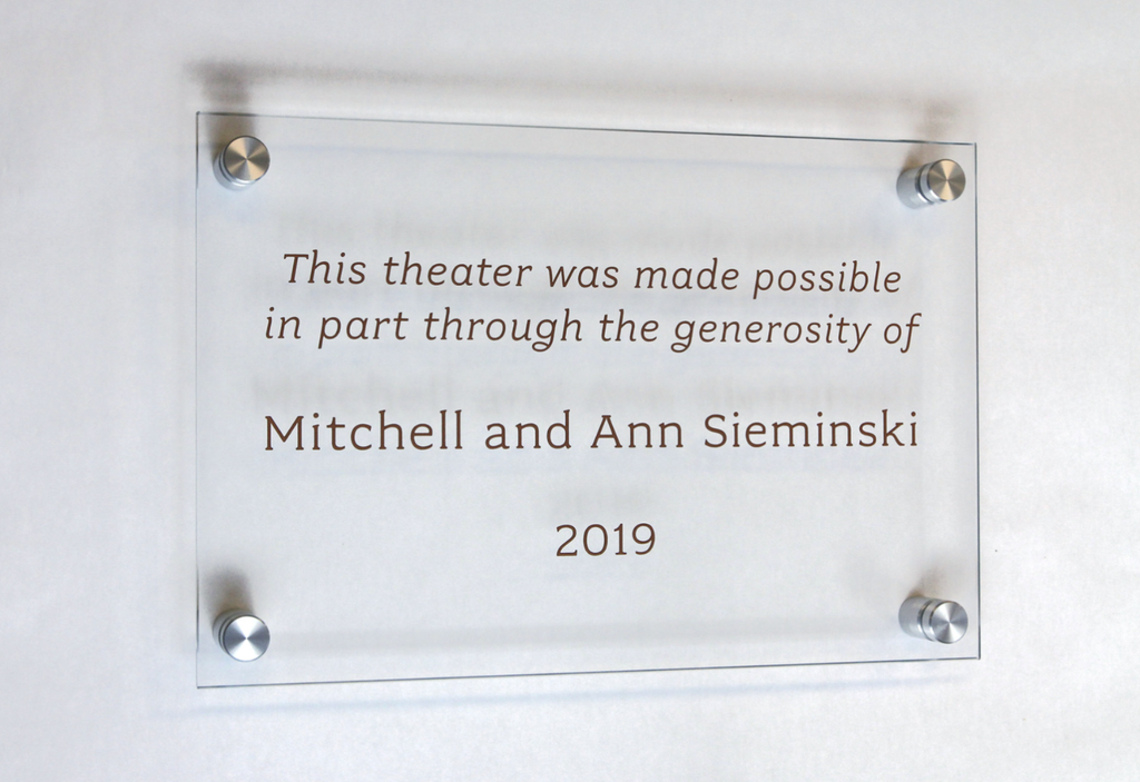 A clear glass donor recognition panel with metallic gold paint fill.