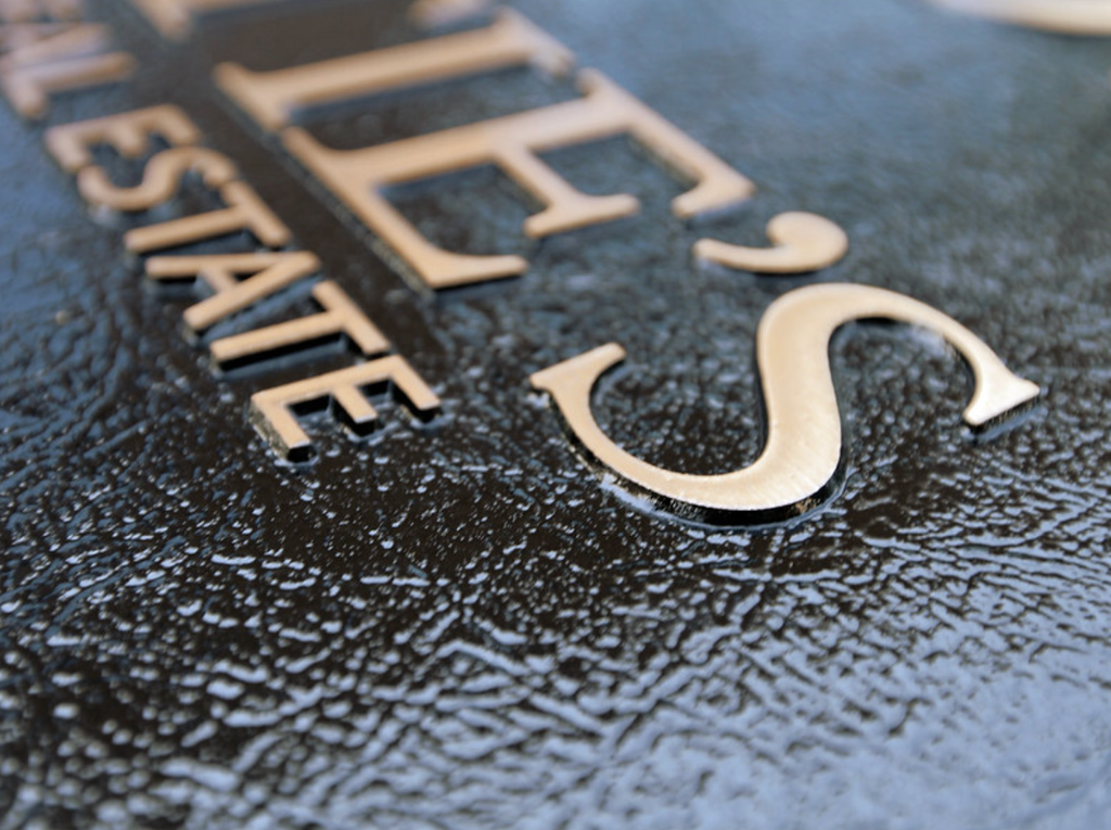 A close-up of a bronze plaque with brushed bronze lettering and dark leathered background details.