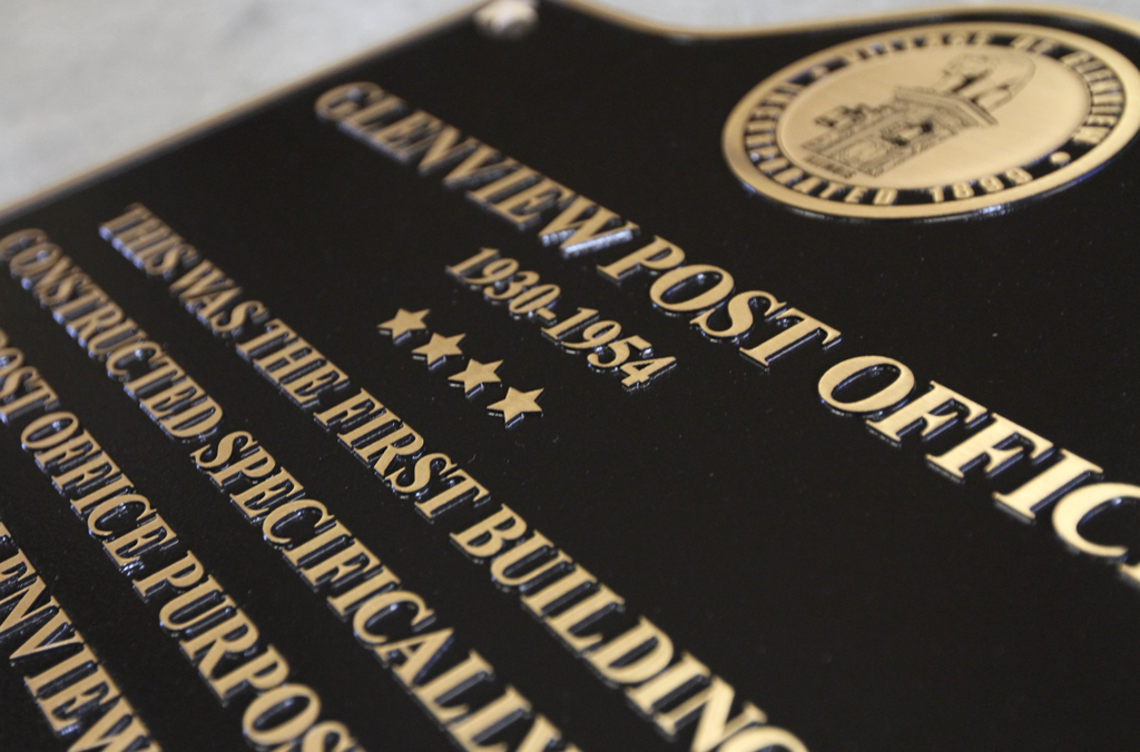 A close-up of a historical bronze plaque with seal and raised lettering.